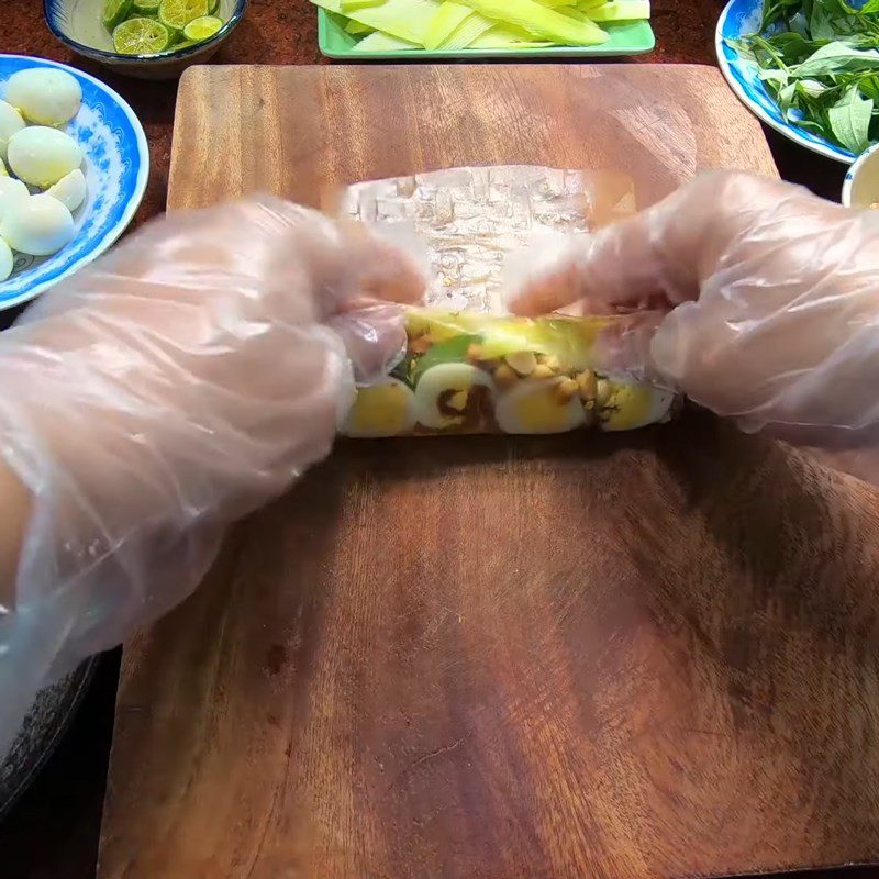 Step 5 Rolling rice paper for red rice paper rolls with quail eggs