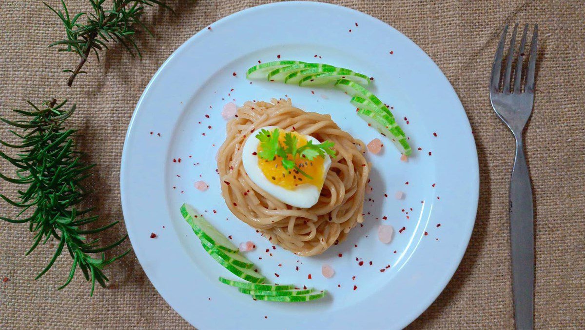 Spaghetti mixed with runny yolk in peanut butter sauce