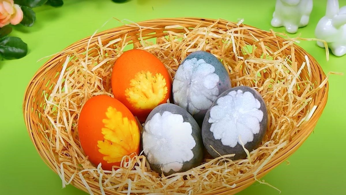 Decorating colored eggs with flowers and leaves